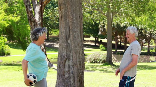 This videory depicts a joyful and active senior couple enjoying their time outdoors by playing with a soccer ball. It is a perfect representation of leisure and healthy lifestyles among senior citizens, suitable for use in promotions related to retirement communities, fitness and wellness for older adults, or advertisements for outdoor activities and family-friendly outings.