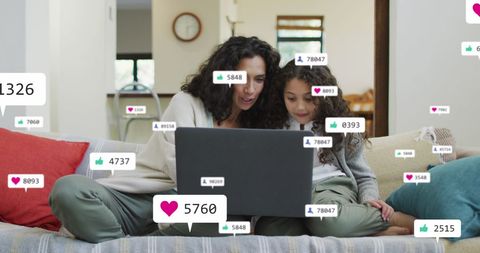 Mother and daughter engaged with social media on laptop