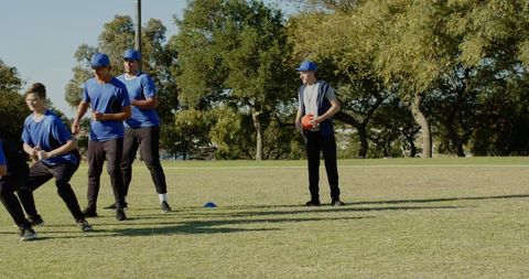 Coach holding red ball and whistle coaching youth team training drill on grass field