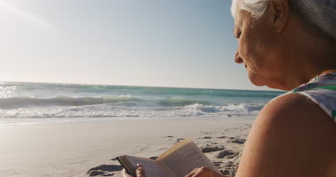 Senior Woman Relaxing and Reading on Beachfront Tranquility