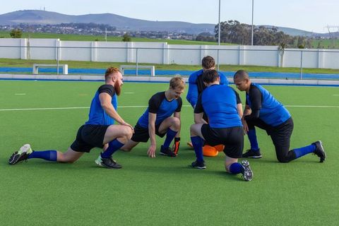 Dynamic sports team strategizing in blue uniforms on turf field