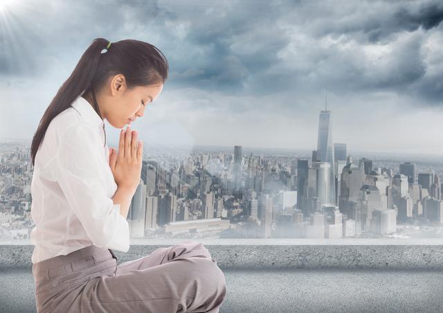 Digital composite of Business woman with flare praying against grey skyline and clouds