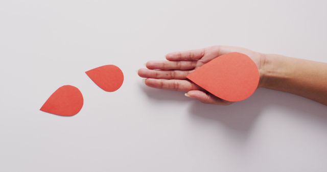 Hand Holding Red Paper Raindrop Cutouts on White Background - Download Free Stock Images Pikwizard.com