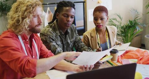 Collaborating fashion designers reviewing sketches and fabric swatches in creative studio