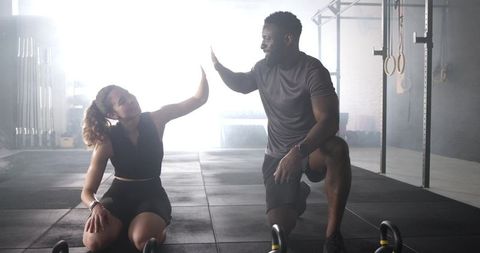 Diverse trainer and client sharing high-five in ambient fitness studio