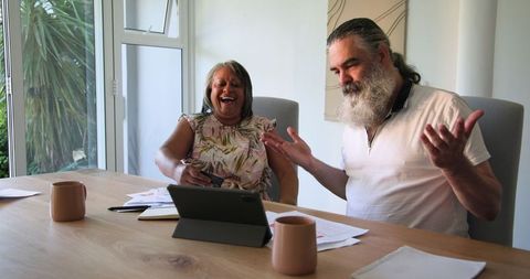 Senior Couple Discussing on Tablet Over Coffee at Home