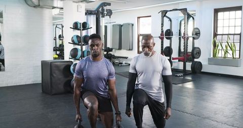 Workout partners doing lunges in modern gym with kettlebells