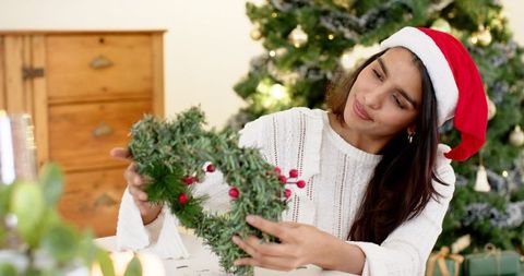 Woman Crafting Green Wreath in Festive Santa Hat on Christmas