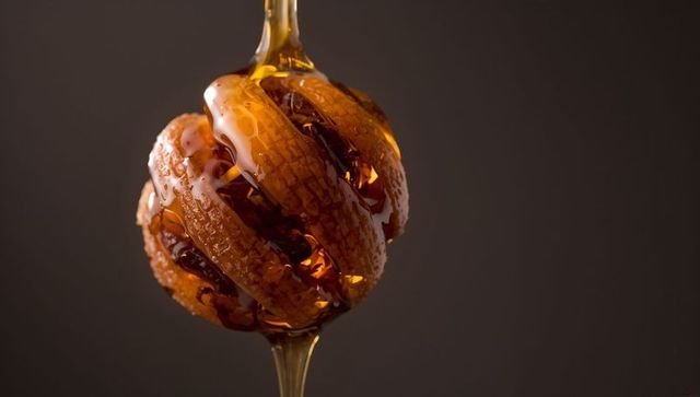 Dripping Honey on Grooved Wooden Dipper Macro Closeup with Glossy Amber Syrup