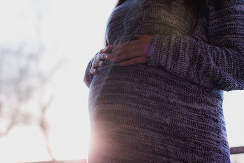 Pregnant woman embracing maternity with radiant backlight