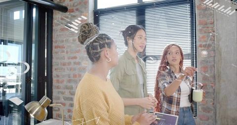 Creative team brainstorming in modern loft office collaborating over tablet and coffee