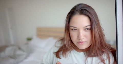 Contemplative Woman Sipping Tea in Comfortable Bedroom