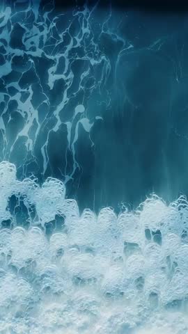 Vertical ocean foam motion showing waves pushing lacy foam clusters upward, abstract marine