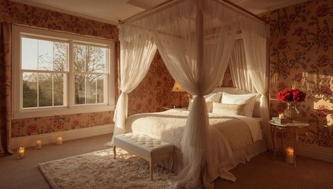 Sunlit vintage four-poster canopy bed draped in sheer curtains in romantic floral bedroom