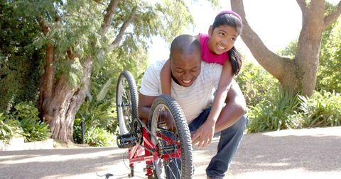 Father and Daughter Bonding Over Bicycle Repair in Park