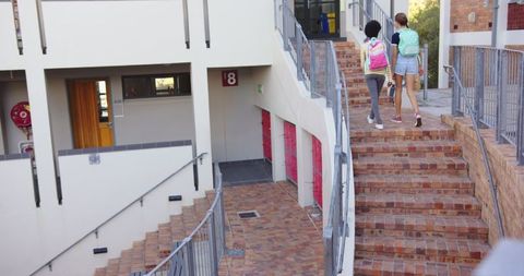 Two Female Students Climbing School Staircase with Backpacks