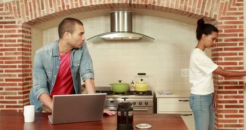Couple balancing work and home duties in kitchen environment