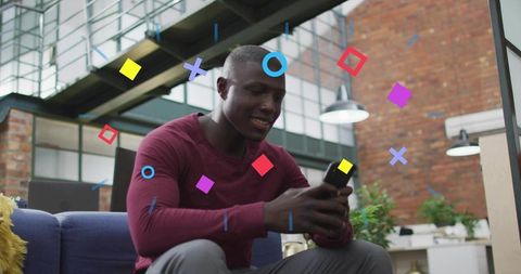 Man using smartphone on modern loft sofa with vibrant geometric graphic overlays