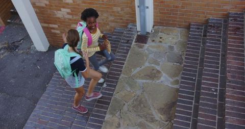 Two Diverse Girls Climbing School Steps with Backpacks