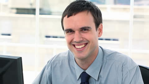 Smiling Businessman at Office Desk Conveying Positivity