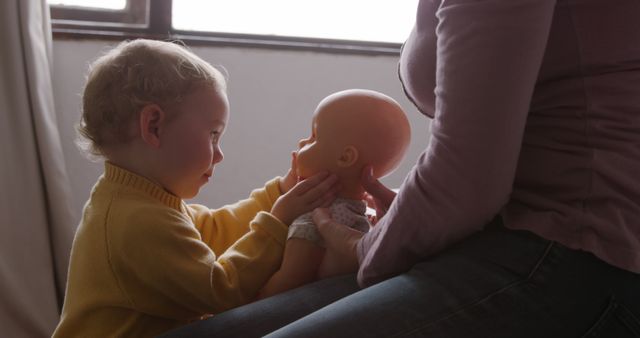 Curious Toddler Playing with Doll on Mother's Lap - Download Free Stock Images Pikwizard.com