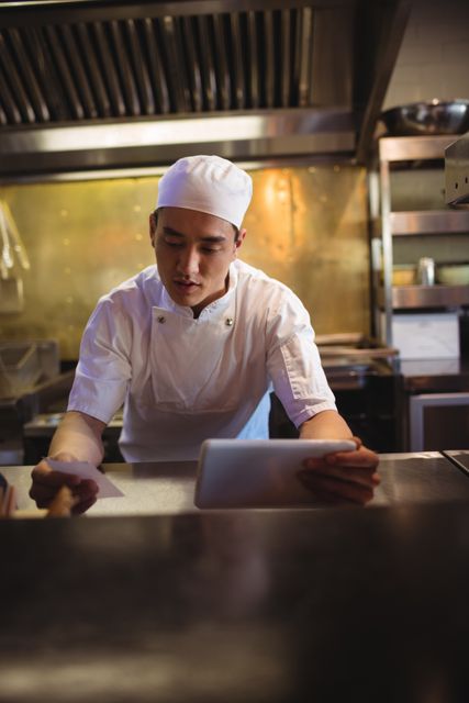 Chef holding digital tablet while looking at an order list in the commercial kitchen