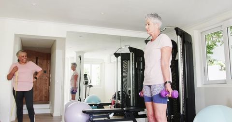 Happy senior lesbian couple exercising together at home gym