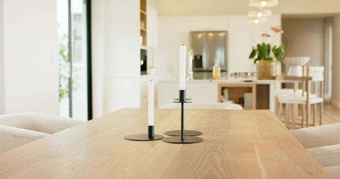 Minimalist black candlesticks on light wood dining table in bright modern kitchen