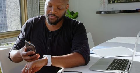 Man using smartwatch and smartphone in modern home environment