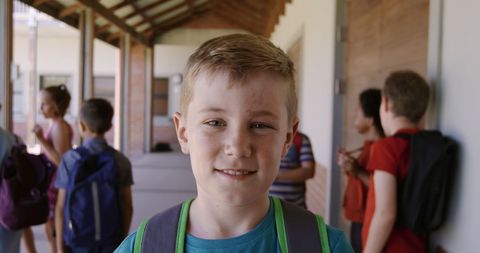 Smiling caucasian schoolboy in school corridor