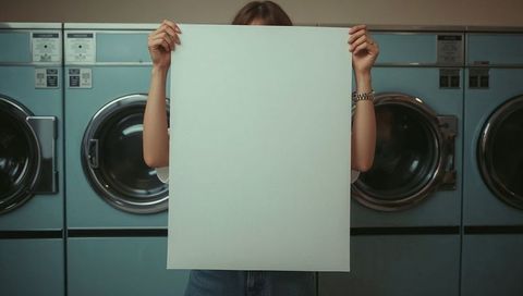 Person holding blank white board in modern laundromat
