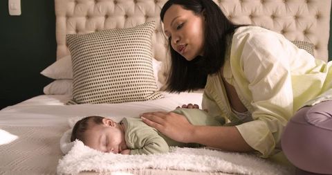 Mother Gently Cradling Sleeping Infant on Bed