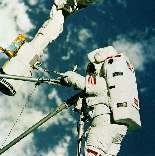Astronaut performing extravehicular activity during STS-49 mission on Orbiter Endeavour in 1992. Connecting struts in space, showcasing teamwork and cutting-edge technology. Suitable for illustrating space exploration history, NASA missions, space walks, technology in space, or teamwork in extreme conditions.