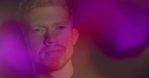 Thoughtful male portrait with magenta and purple bokeh light effects