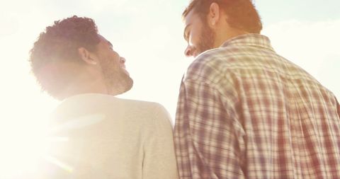 Two Young Men Engaged in Friendly Conversation with Sunlit Background