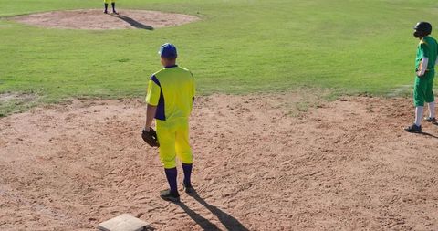 Baseball Player Standing on Infield Near Base Wearing Bright Yellow and Blue Uniform