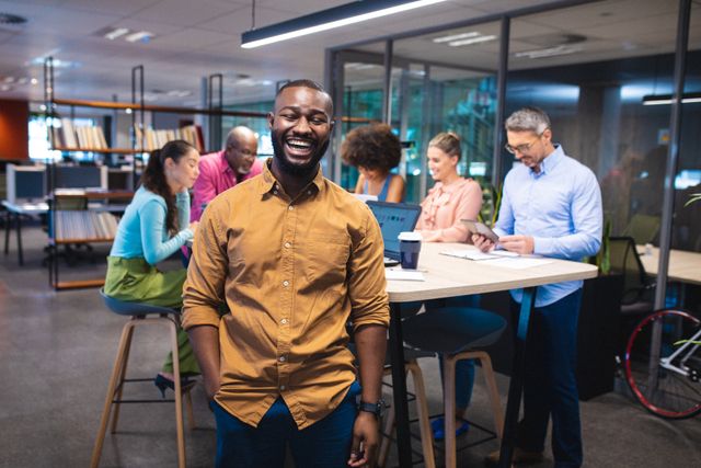 Portrait of cheerful african american businessman with multiracial colleagues in background. unaltered, business, teamwork, corporate business, occupation and modern office concept.