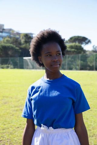 Confident girl standing on soccer field in sportswear