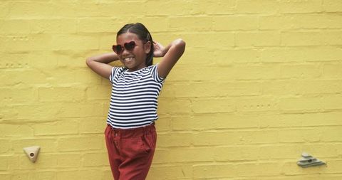 Confident Young Girl Smiling with Vibrant Style Against Yellow Wall