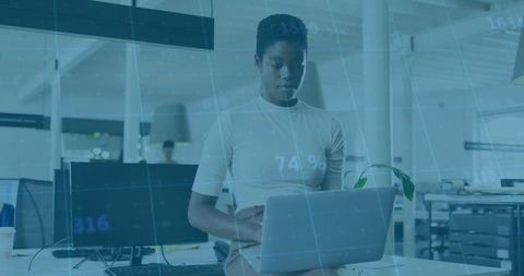 Professional typing on laptop with analytics overlay in modern urban open office workspace