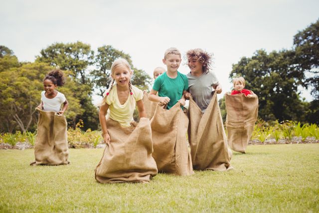 Children having a sack race in park on a sunny day