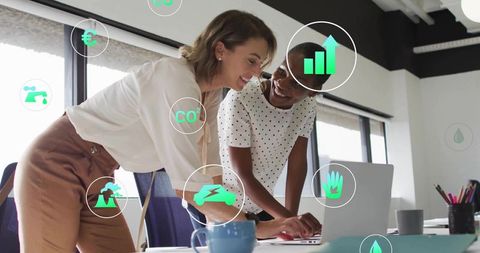 Collaborating Women Analyzing Data on Laptop in Modern Office