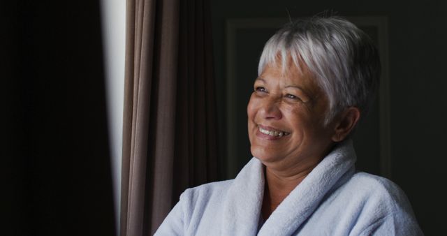 Smiling Senior Woman in Bathrobe Looking Out Window - Download Free Stock Images Pikwizard.com