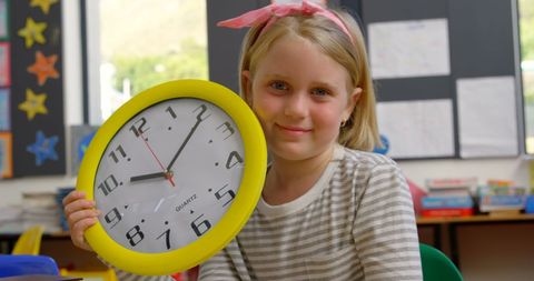 happy schoolgirl in classroom with wall clock - Download Free Stock Images Pikwizard.com