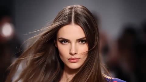 Runway Model Striding Toward Camera Under Lights, Hair Blowing, Showcasing Patterned Garment