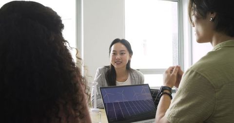Diverse business meeting analyzing renewable energy on laptop