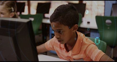 Boy concentrating on coding at computer in modern classroom with binary digital overlay