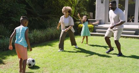 Family playing soccer outdoors engaging in happy recreation
