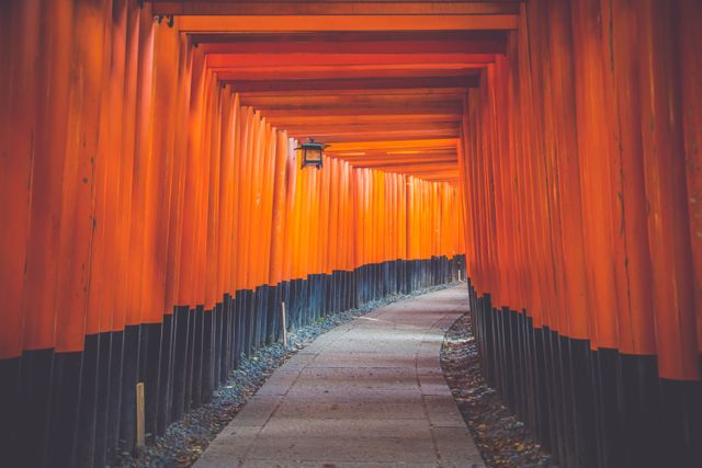 Capturing traditional red torii gates forming a pathway at the iconic Fushimi Inari Shrine in Kyoto, Japan. Ideal for use in travel blogs, cultural presentations, architectural studies, and tourism promotions.