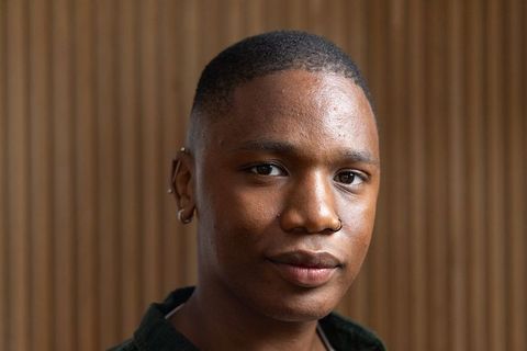 Confident african american man portrait with nose hoop and earrings, wood slat background